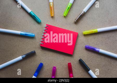 Notepad for notes with red sheets. Blank space for notes. Mocap. On warm ochre kraft background. Small spring-loaded notebook resting on table surroun Stock Photo