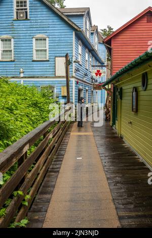Ketchikan, AK - 10 June 2022: Tourist in the rain on Creek Street boardwalk in Ketchikan Alaska Stock Photo