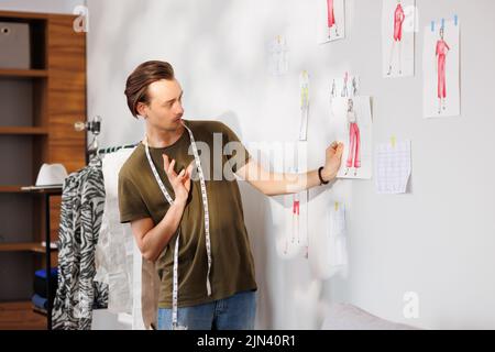 A young guy, a fashion designer, looks at his sketches of the new collection Stock Photo