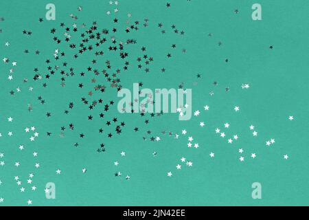 Star shaped glitter confetti on green background, festive backdrop, emerald color Stock Photo