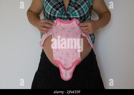 Image of a woman's baby bump showing the pink dress she just bought for the baby girl on the way. Stock Photo