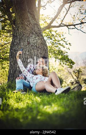 We make such a cute couple. a young couple taking a selfie while spending the day at the park. Stock Photo