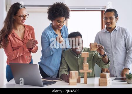 Making waves in the industry with a new business model. a group of young businesspeople having a meeting with building blocks in a modern office. Stock Photo