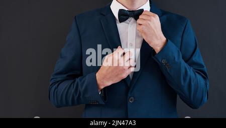 Its his day, hes gotta have the best tie. an unrecognizable bridegroom adjusting his bowtie in preparation for his wedding. Stock Photo