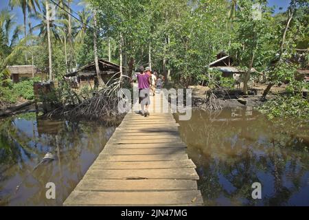 Villagers walking on a wooden walkway built above coastal wetland in Horale village, Seram Utara Barat, Maluku Tengah, Maluku, Indonesia. Stock Photo