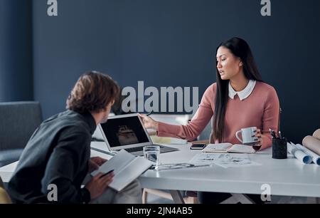Caffeine always boosts our creativity. two young architects going over designs on a laptop together in their office. Stock Photo