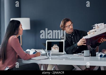 We need to look at this from a different angle. two young architects working together on a scale model of a modern house in their office. Stock Photo