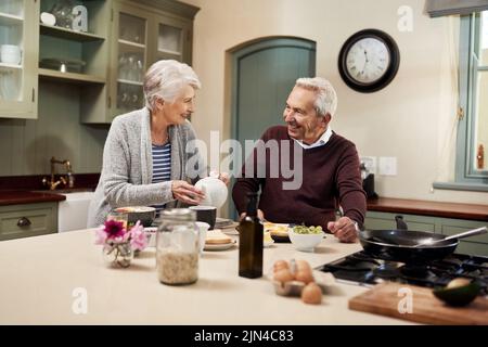 We always enjoy having breakfast together. an affectionate senior couple having a meal together in the kitchen at home. Stock Photo