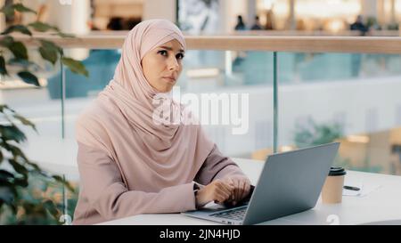 Thoughtful pensive worried young arab woman writer working on laptop thinks new idea startup develops plan writes novel finds solution to problem Stock Photo