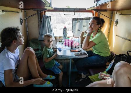 August 6, 2022, Donetsk Oblast, Donets'ka Oblast'', Ukraine: A mother and her children are seen on the evacuation train to Dnipro. Amid the intensified fighting in the Eastern part of Ukraine, east Ukraine is now intensifying its civilian evacuation, as millions of Ukrainian families have been evacuating from the closer and closer war, as many of them will be relocated to the western part of the country.According to the United Nations, at least 12 million people have fled their homes since Russia's invasion of Ukraine, while seven million people are displaced inside the country. (Credit Ima Stock Photo