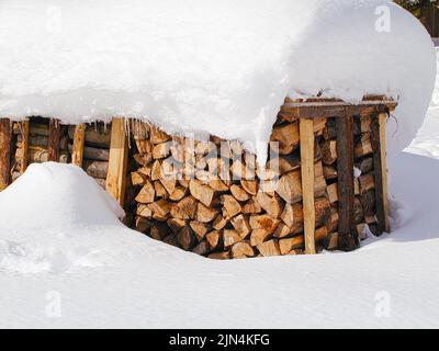 Tyrol, Austria. February 2014. A pile of firewood, covered with snow. Close uo. Stock Photo