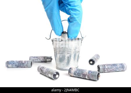 Used batteries recycling concept. Hand collects dead batteries in a bucket. Stock Photo
