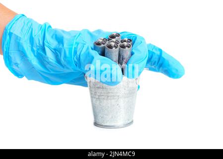 Throwing dead corroded batteries in a small steel bucket isolated on white. Cells recycling concept. Stock Photo