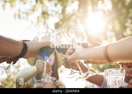 Close up of people toasting with wine glasses lit by sunlight during Summer celebration, copy space Stock Photo
