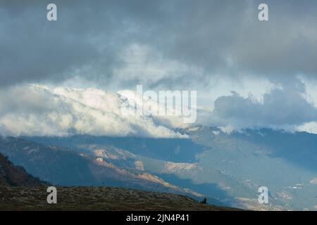 Low clouds of the mountain. Majestic huge clouds hung over the valley of the mountains. Atmospheric sunny landscape. The concept of travel, the beauty Stock Photo
