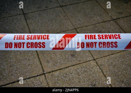 Red and white striped fire services safety tape, with a warning of do not cross. Stock Photo