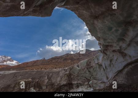 View of snow capped mountains from a cave carved into the Vallelunga glacier ice Stock Photo