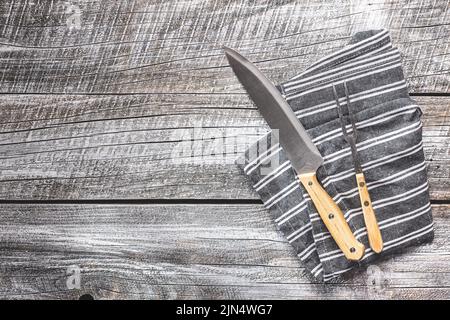 Knife and fork on napkin on a wooden table. Stock Photo