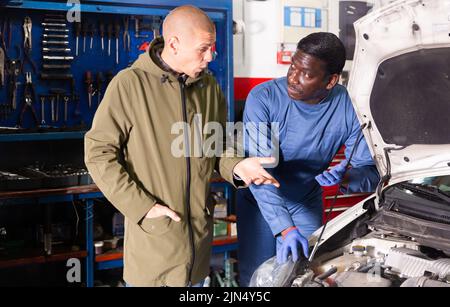 Owner of car explains the problem with car engine to mechanic of the car service Stock Photo