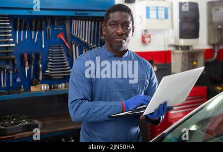 Mechanic using a laptop to work in service Stock Photo