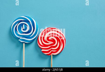Colorful swirl round candy lollipops on blue background. Stock Photo