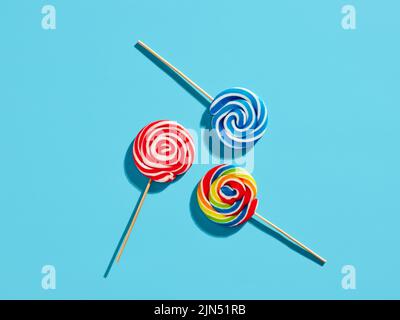 Colorful swirl round candy lollipops on blue background. Stock Photo