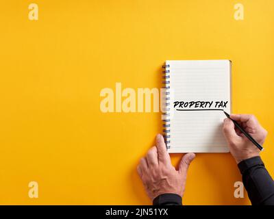 Male hand writing property tax on a notepad. Stock Photo