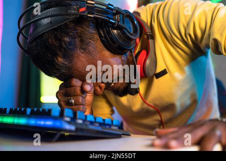 close up shot of Gamer with headphones sad due to loss while playing video game on computer at home - concept of competition, online streamer and Stock Photo