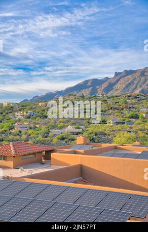 View of a neighborhood from a roof with solar panels at Tucson, Arizona. Solar panels on a roof with a view of a sloped mountainside residential area. Stock Photo