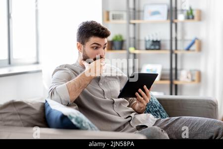 shocked man with tablet computer at home Stock Photo