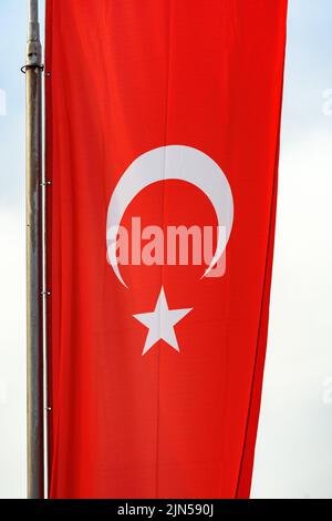 National flag of Turkey or Republic of Turkiye on post. Red banner with white star and crescent. Vertical image. Stock Photo