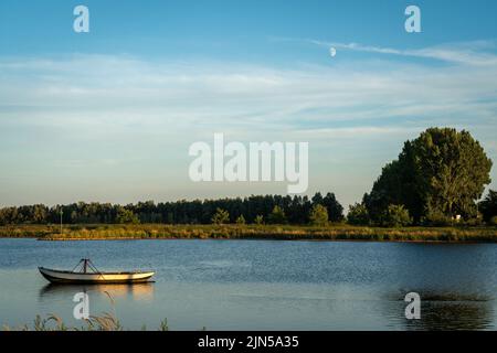 Sunset scenery with the boat at the banks of river Nederrijn, nearby the Blauwe Kamer nature reserve Stock Photo