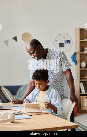 African mature teacher teaching his pupil at table at home during home schooling Stock Photo