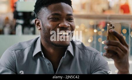 Happy confident young businessman holding phone looking at screen talking on webcam interview with employer smiling guy speaking by video call on Stock Photo