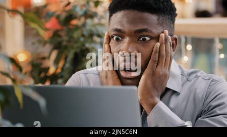 Close-up young businessman looking at laptop screen getting bad news surprised shocked man holding head found error incorrectness in electronic Stock Photo