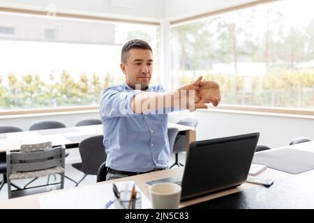 tired man with laptop stretching at home office Stock Photo