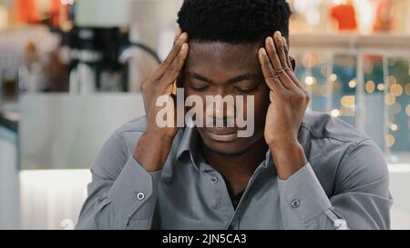 Portrait young sad tired young guy suffering from headache rubs temples serious upset man feeling pain painful sensations migraine symptom pressure Stock Photo