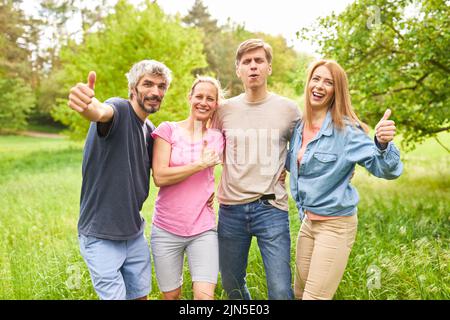 Group of young people with thumbs up on summer vacation on a green meadow Stock Photo