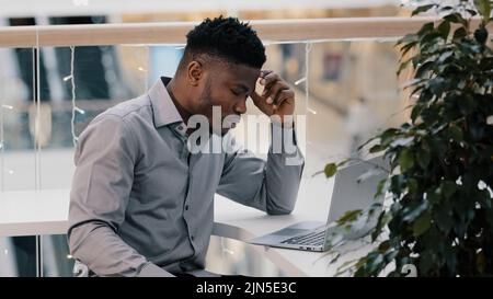 Shocked young businessman working on laptop feeling frustrated stressed by problem despair unsuccessful results unsaved information loss of network Stock Photo