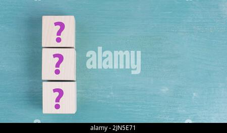 Three wooden cubes with question marks in purple color, searching for an answer, customer service Stock Photo