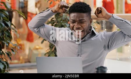 Close-up young excited businessman reads good news by email on laptop amazed happy guy winner celebrates victory celebrating success feels joy winning Stock Photo