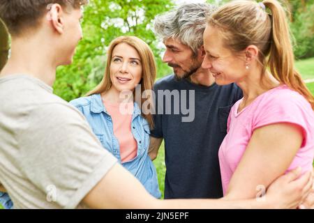 Young people stand in a circle and talk to each other as friends on a summer outing Stock Photo