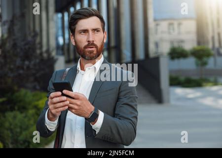 Focused Businessman in suit going home after long working day and using phone Stock Photo