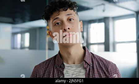 Male portrait young confident proud hispanic guy looking at camera standing indoors serious novice businessman student freelancer model posing in Stock Photo