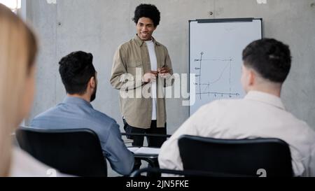 Young male manager presenting project plan to colleagues in meeting explaining report schedule ideas on white board in office making presentation Stock Photo