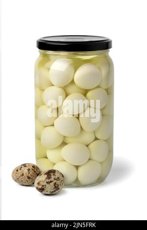 Glass jar with preserved cooked Quail eggs in water close up isolated on white background with fresh raw eggs in front Stock Photo