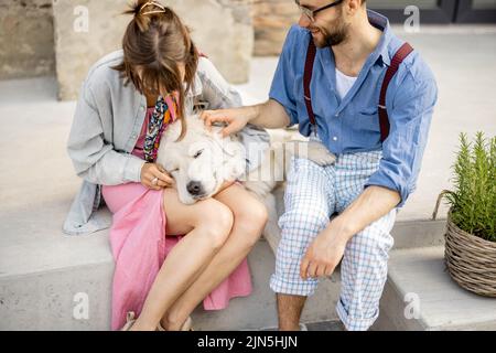 Stylish couple have fun and sit with their dog on a street Stock Photo