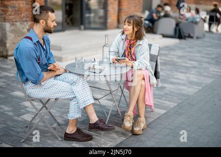 Stylish couple of colleagues have a conversation while sitting at cafe terrace Stock Photo