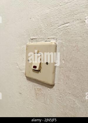 An old fashioned light switch mounted on a white wall Stock Photo