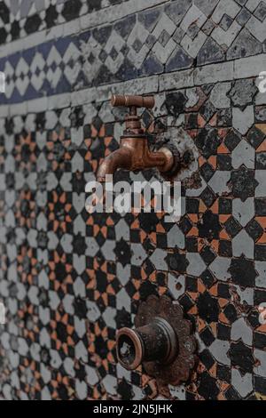 Traditional Moroccan mosaic fountain with a copper tap in the middle of it Stock Photo
